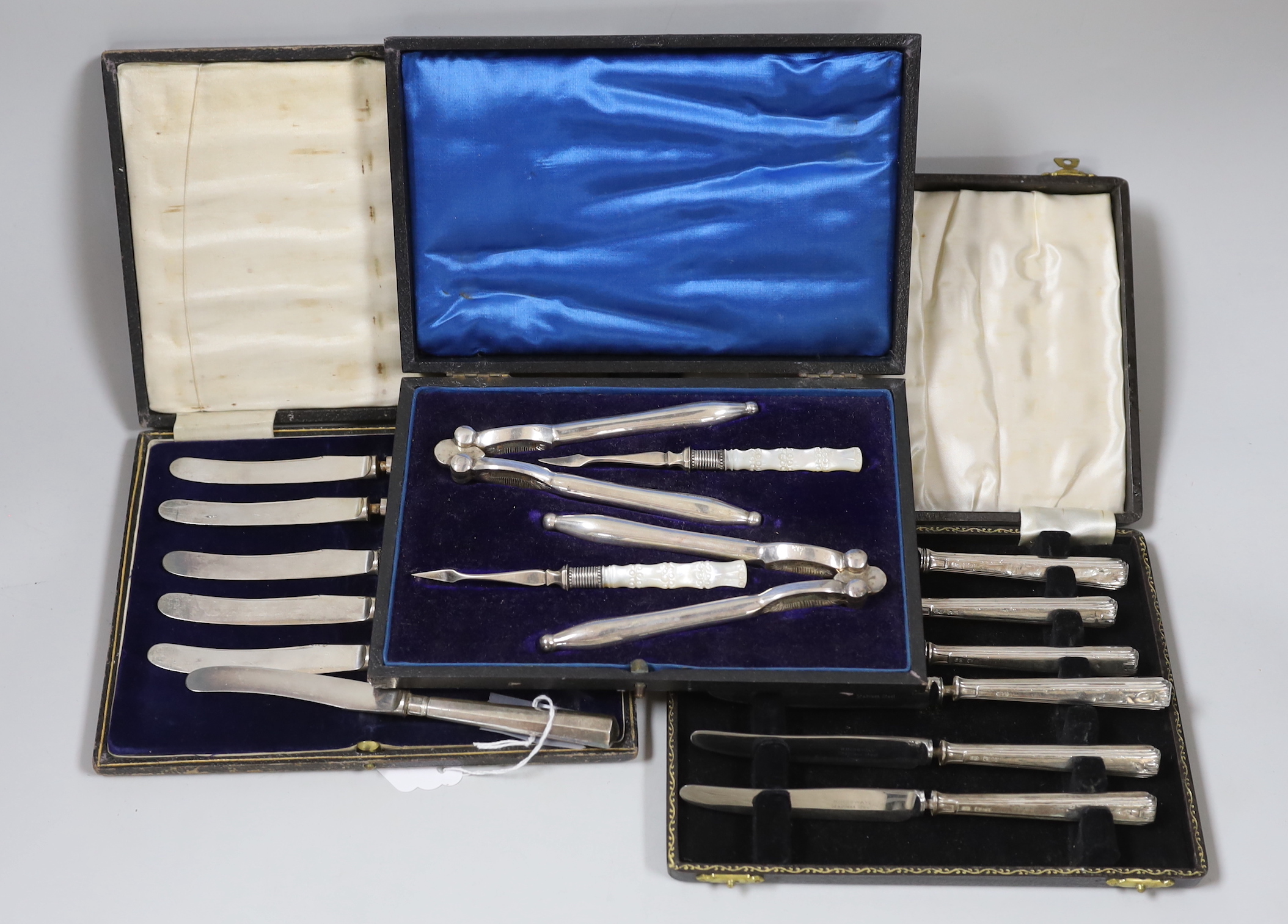 Two cased sets of six silver handled cake knives and cased plated nutcracker set.